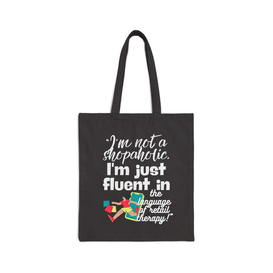 "I'm not a shopaholic; I'm just fluent in the language of retail therapy!"- Cotton Canvas Tote Bag